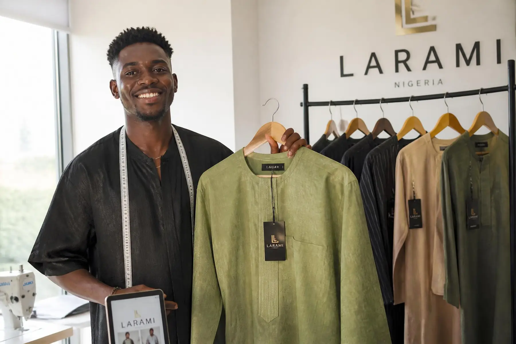 Nigerian fashion designer holding a finished branded garment in a production studio